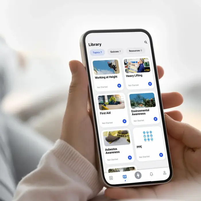 Persona que utiliza una aplicación de smartphone para navegar por una biblioteca de cursos que incluye "Trabajo en altura", "Primeros auxilios" y "Concienciación sobre el amianto", entre otros, con opciones clasificadas por temas y sectores.