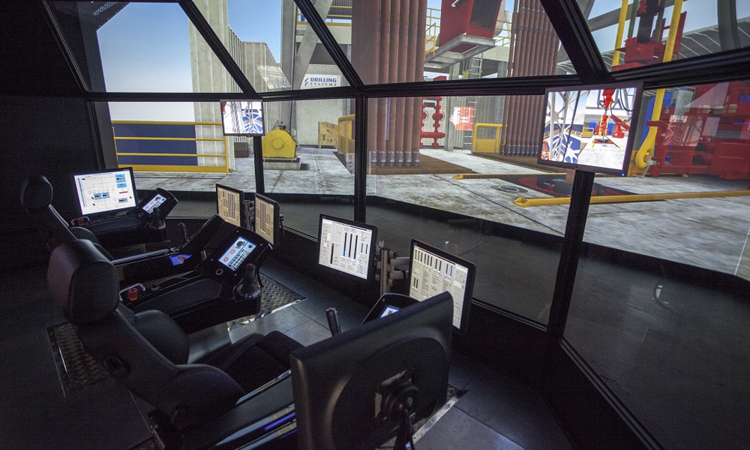 منظر داخلي لغرفة تحكم مزودة بشاشات وكراسي متعددة، تضم شاشات تعرض البيانات وبيئة صناعية محاكاة.