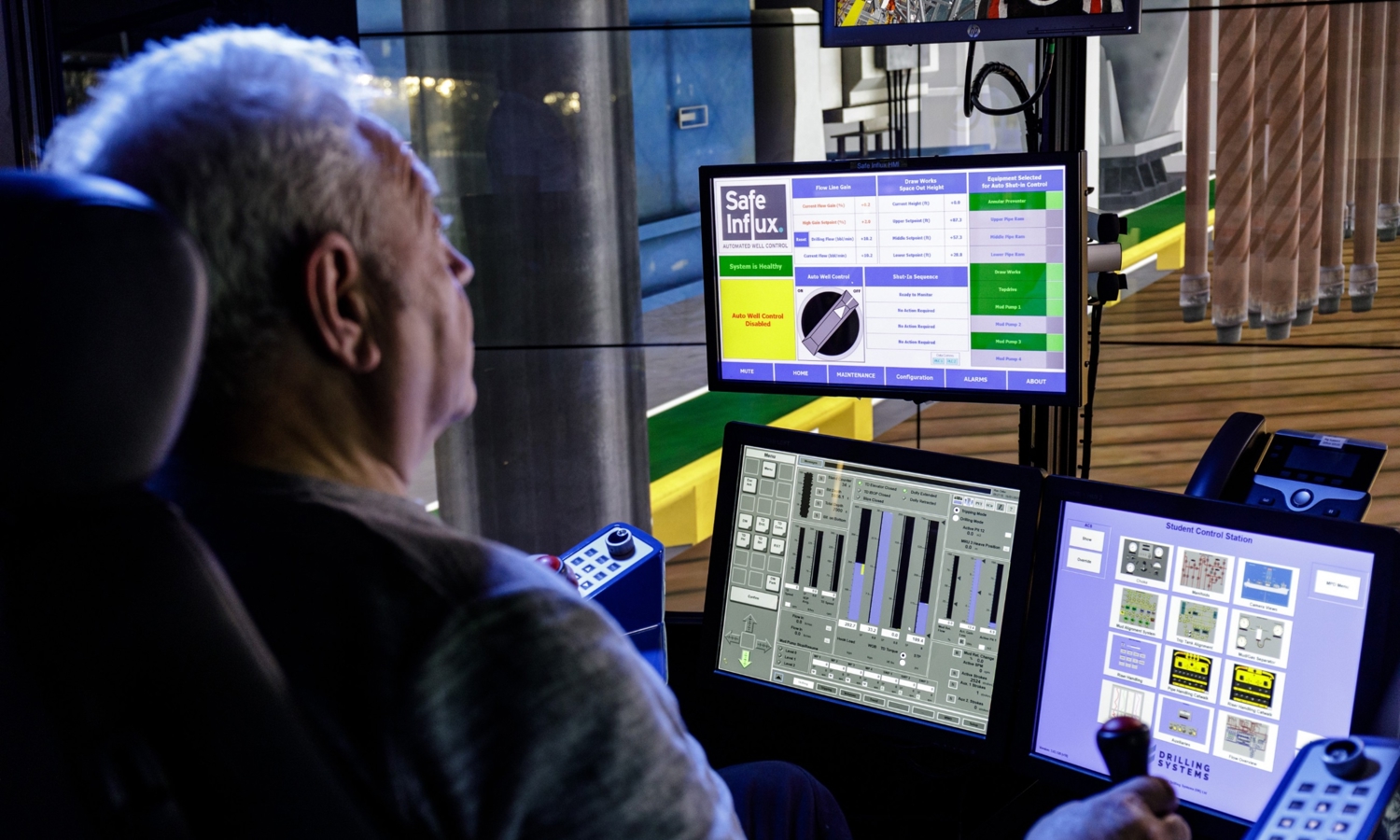Um homem opera uma placa de controlo com vários ecrãs e botões. Os ecrãs apresentam vários gráficos, controlos e informações, incluindo um com a indicação "Safe Influx.