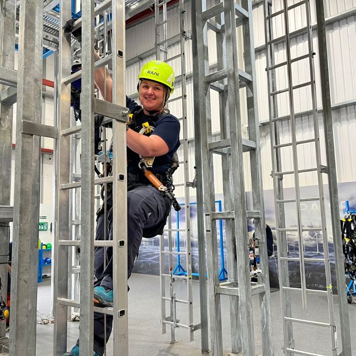 Instrutor 3t com um capacete de néon a subir uma escada para uma formação GWO.