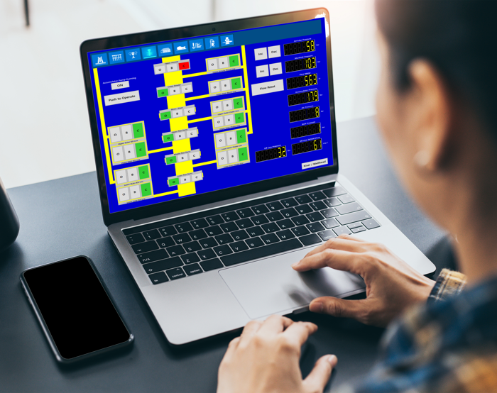 Uma pessoa utiliza um computador portátil que apresenta um fluxograma complexo a azul e amarelo.