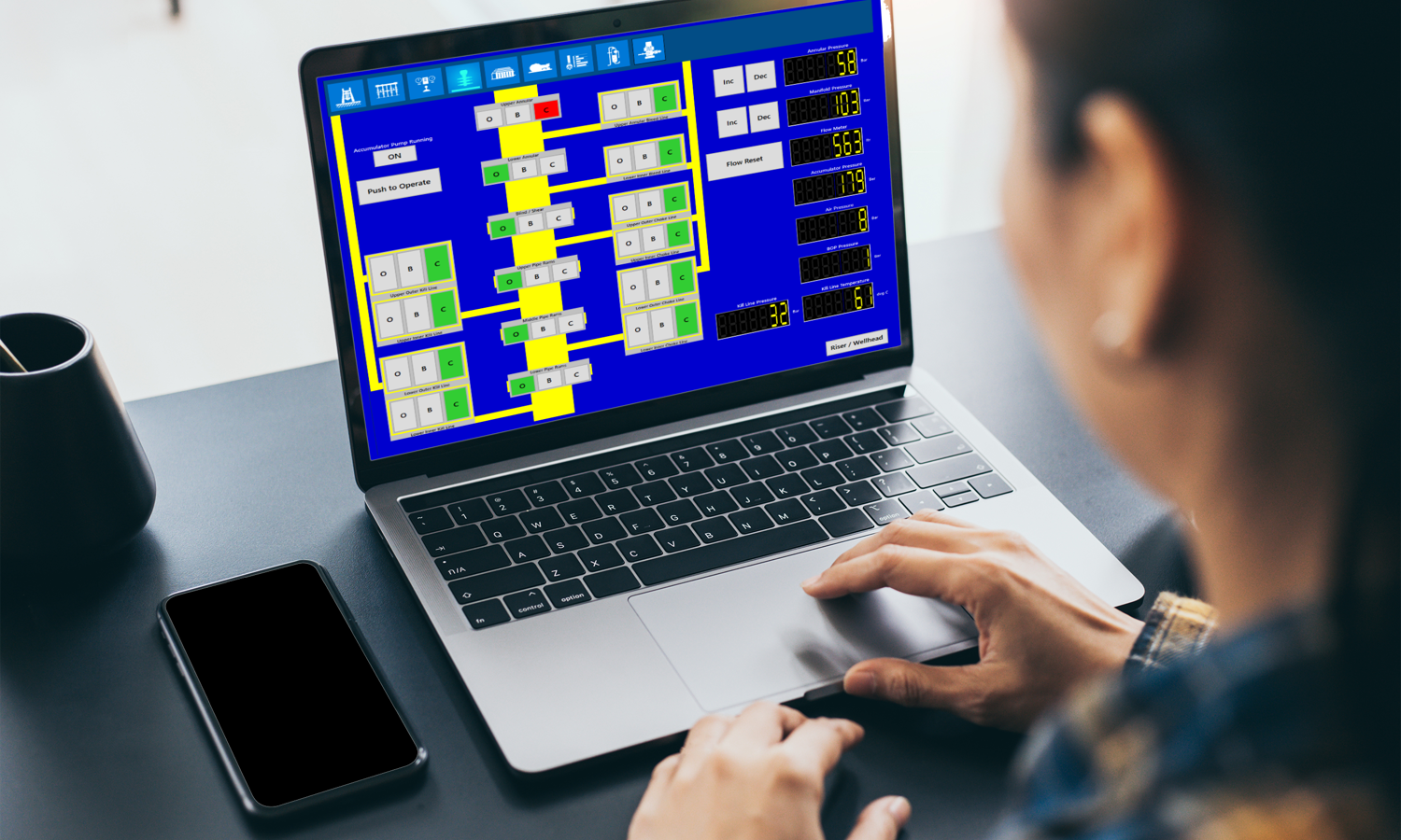 Uma pessoa utiliza um computador portátil que apresenta um fluxograma complexo a azul e amarelo.