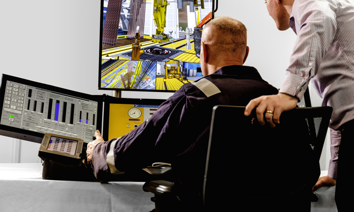 Dois indivíduos observam e interagem com dados e simulações em vários monitores numa sala de controlo. A cena inclui equipamento industrial apresentado nos ecrãs.