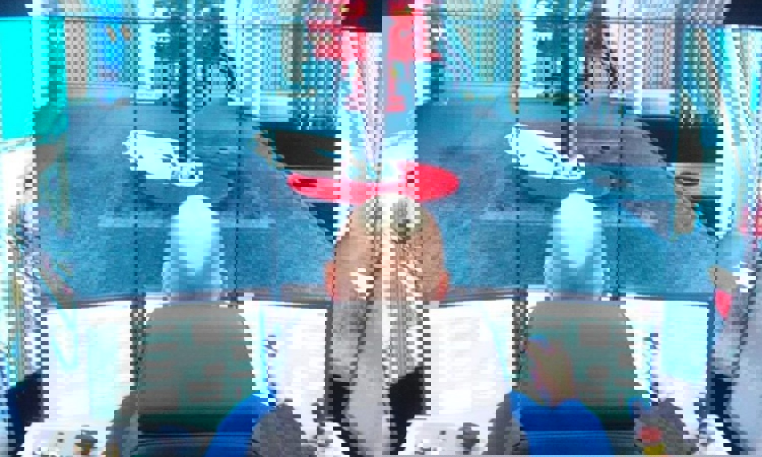 Uma pessoa opera um painel de controlo com vários ecrãs que apresentam um ambiente industrial, possivelmente uma simulação ou monitorização de máquinas.