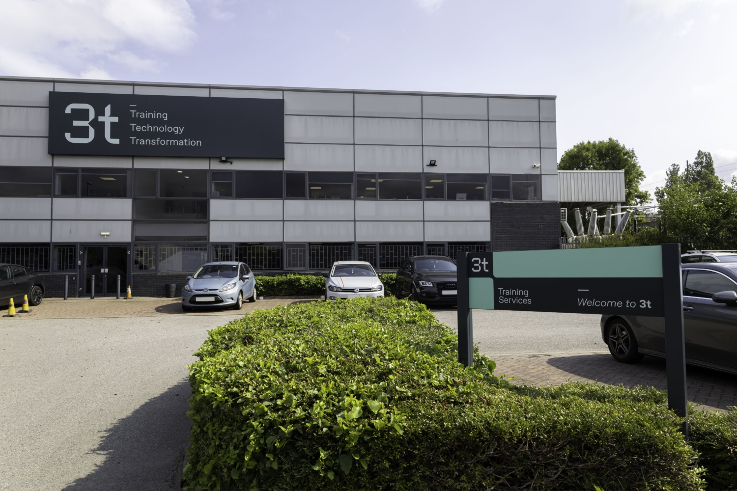 Fotografia exterior do edifício cinzento com parque de estacionamento