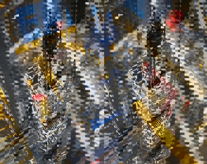 Vista de grande plano de uma plataforma de perfuração offshore mostrando maquinaria, barreiras de segurança e plataformas com corrimões, vista de um ângulo elevado.