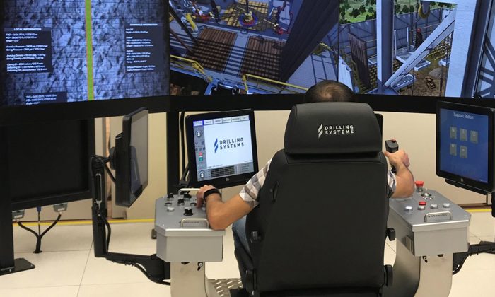 يقوم شخص بتشغيل نظام محاكاة حفر عالي التقنية مزود بشاشات ولوحات تحكم متعددة، يُرجح استخدامه لأغراض التدريب أو الاختبار.