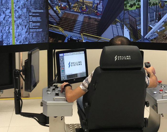 يقوم شخص بتشغيل نظام محاكاة حفر عالي التقنية مزود بشاشات ولوحات تحكم متعددة، يُرجح استخدامه لأغراض التدريب أو الاختبار.