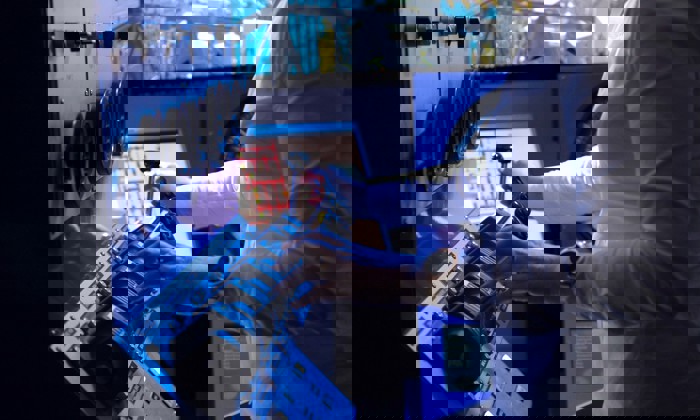 شخص يشغل لوحة تحكم مزودة بمفاتيح وأقراص، يرتدي قميصاً أبيض طويل الأكمام وساعة ذكية.