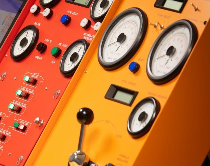 Grande plano de dois painéis de controlo, um vermelho e outro amarelo, com vários mostradores, interruptores, botões e medidores, indicando a instrumentação para máquinas ou equipamento técnico.