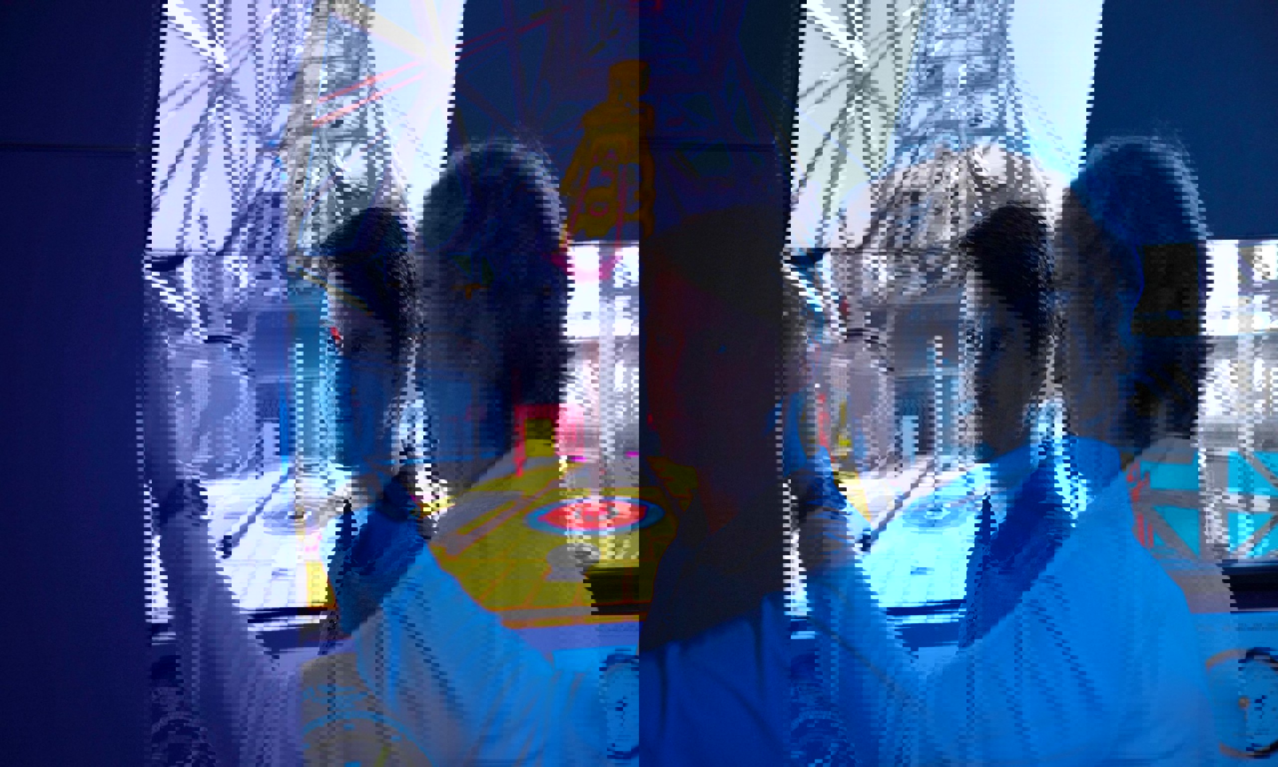 يقوم رجلان في غرفة تحكم بتشغيل جهاز محاكاة مزود بشاشة كبيرة تعرض الجزء الداخلي لمكان صناعي. يشير أحدهما بينما يراقب الآخر باهتمام.